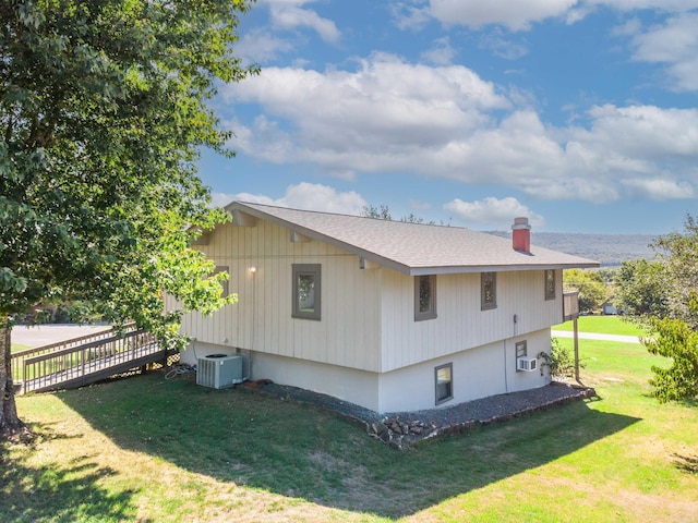 view of side of home with a lawn and cooling unit