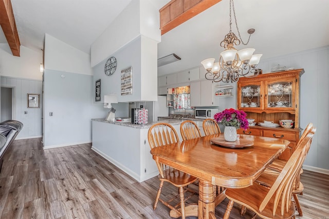 dining space featuring an inviting chandelier, lofted ceiling with beams, and light hardwood / wood-style floors