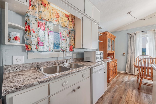 kitchen featuring white appliances, white cabinetry, vaulted ceiling, and sink