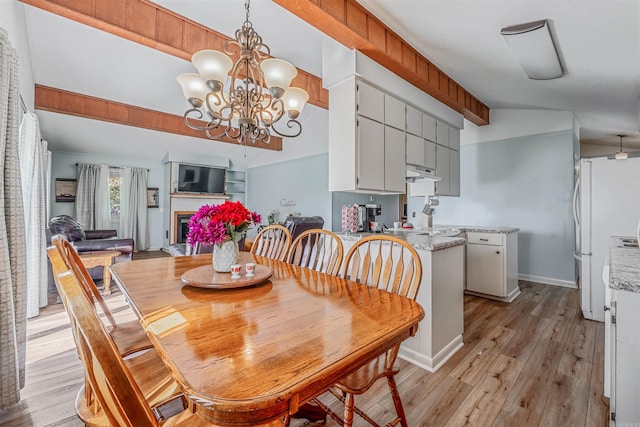 dining room featuring light hardwood / wood-style flooring, vaulted ceiling with beams, and a notable chandelier