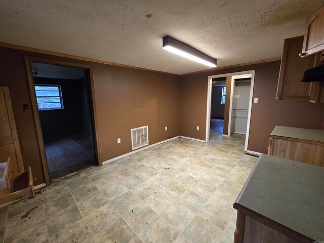 interior space with a textured ceiling and ornamental molding