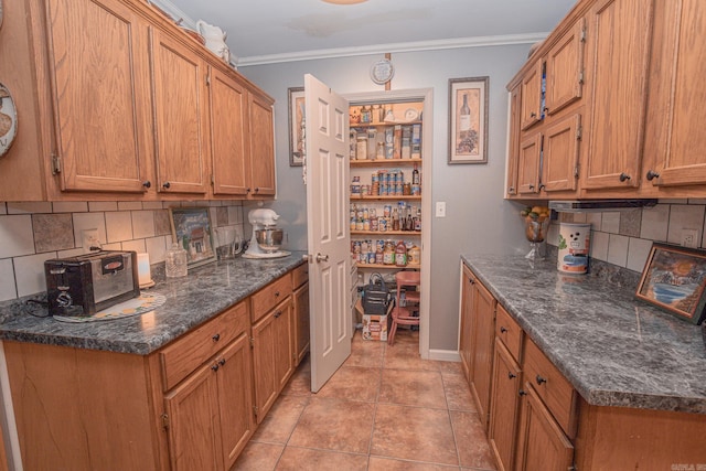 kitchen featuring built in desk, crown molding, light tile patterned flooring, and decorative backsplash