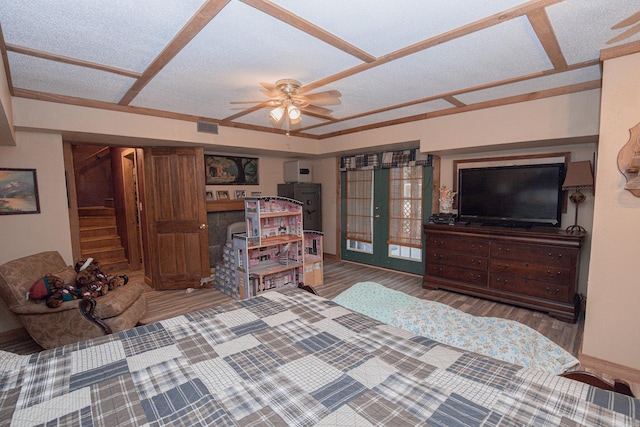 bedroom with a textured ceiling, hardwood / wood-style floors, ceiling fan, and french doors