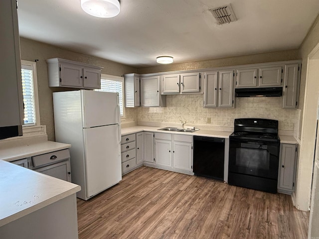 kitchen with hardwood / wood-style flooring, sink, decorative backsplash, and black appliances