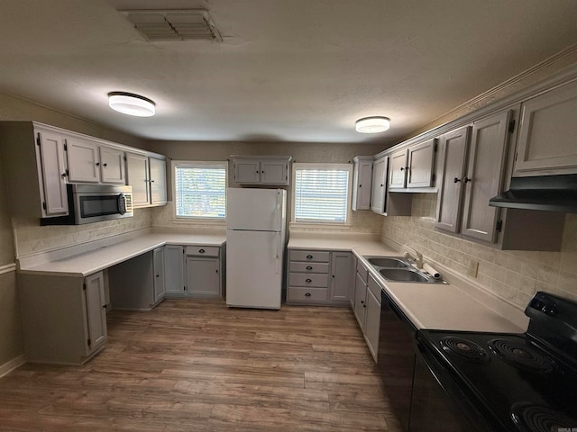 kitchen featuring sink, gray cabinetry, black appliances, backsplash, and hardwood / wood-style floors