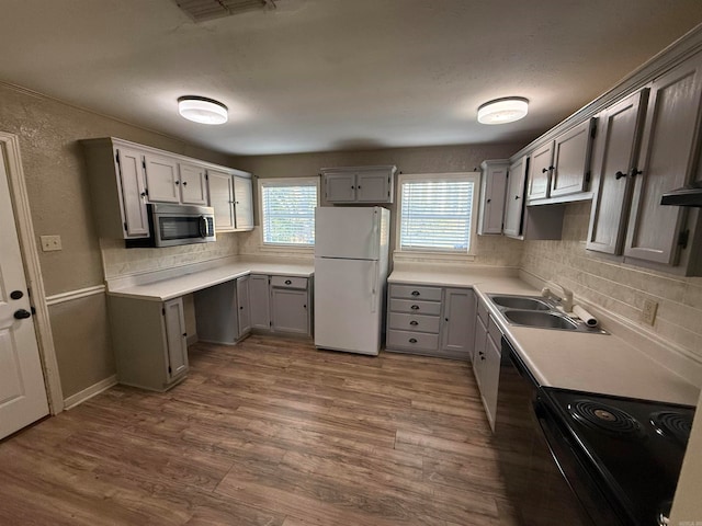 kitchen featuring sink, white fridge, gray cabinetry, black range with electric cooktop, and hardwood / wood-style floors