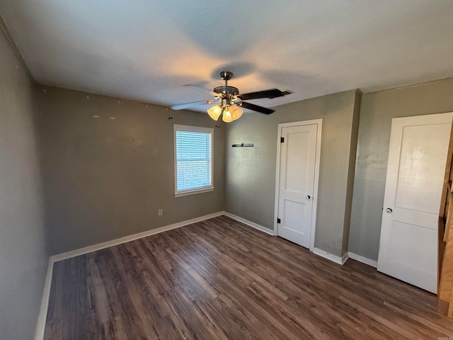 unfurnished bedroom with ceiling fan and dark wood-type flooring