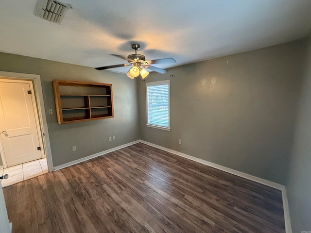 empty room featuring ceiling fan, dark wood-type flooring, and a textured ceiling