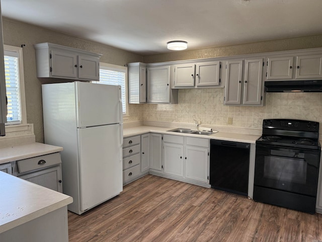 kitchen with a wealth of natural light, black appliances, sink, and dark hardwood / wood-style flooring