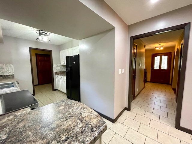 kitchen with black refrigerator with ice dispenser, decorative backsplash, and white cabinetry