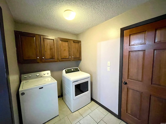 washroom featuring a textured ceiling, light tile patterned floors, washer and dryer, and cabinets