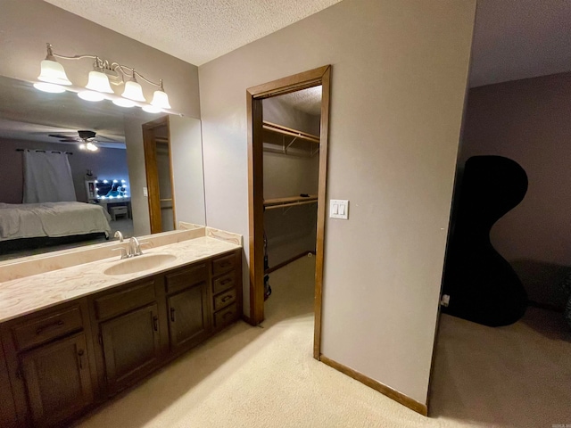 bathroom with a textured ceiling, vanity, and ceiling fan