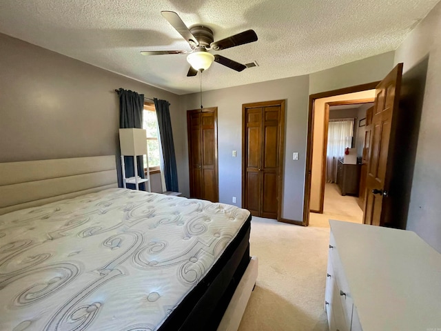 bedroom featuring ceiling fan, a textured ceiling, and light carpet