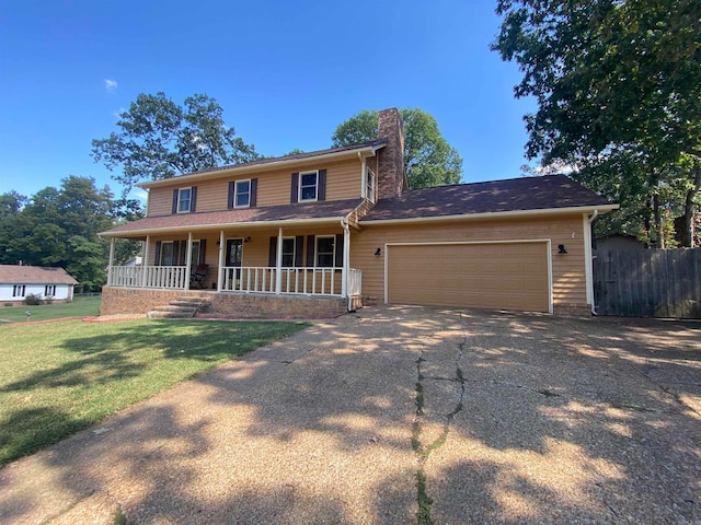 view of front of property featuring a garage, a front lawn, and covered porch