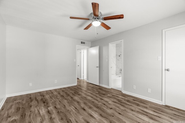 unfurnished bedroom featuring ceiling fan, ensuite bath, and dark wood-type flooring