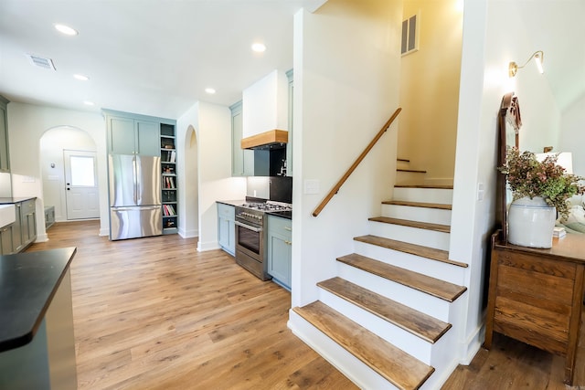 kitchen with light hardwood / wood-style flooring, stainless steel appliances, and custom exhaust hood