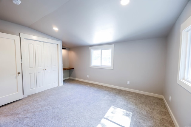 unfurnished bedroom featuring carpet, vaulted ceiling, and a closet