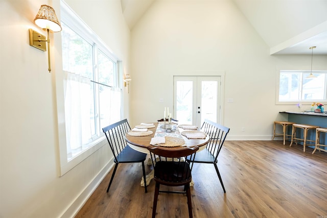 dining area with high vaulted ceiling, french doors, and hardwood / wood-style flooring