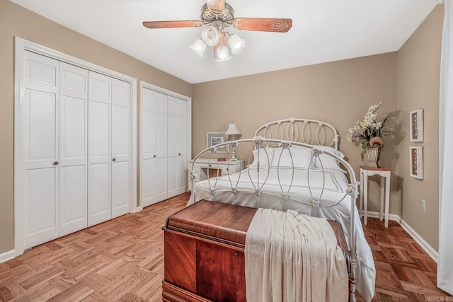 bedroom featuring ceiling fan, two closets, and light parquet flooring