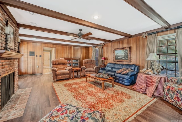 living room featuring a brick fireplace, beam ceiling, wood walls, and hardwood / wood-style floors