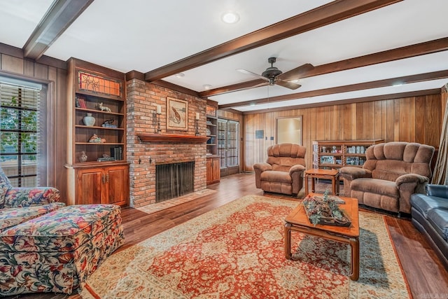 living room with wood-type flooring, a fireplace, wood walls, and beamed ceiling