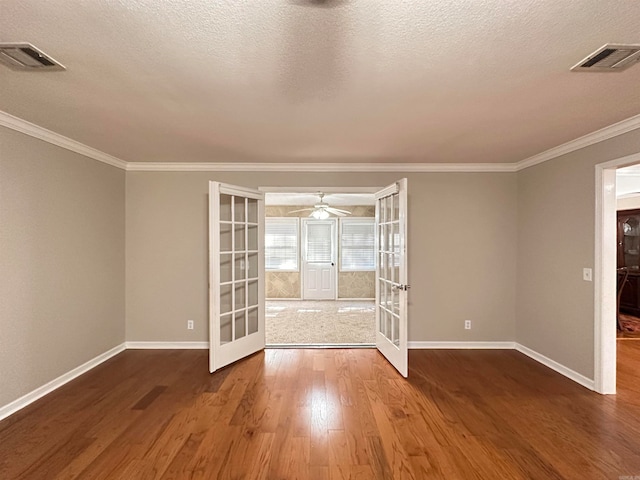 empty room with ceiling fan, ornamental molding, french doors, a textured ceiling, and hardwood / wood-style flooring