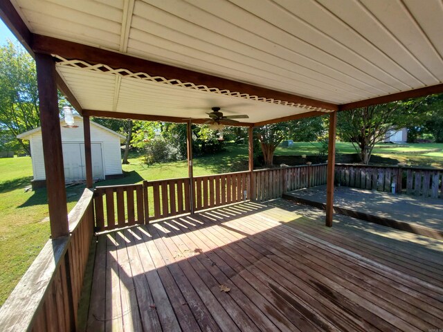 wooden deck featuring ceiling fan, a storage shed, and a lawn