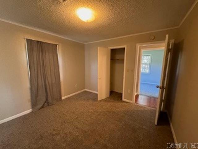 unfurnished bedroom featuring a textured ceiling, crown molding, and dark colored carpet