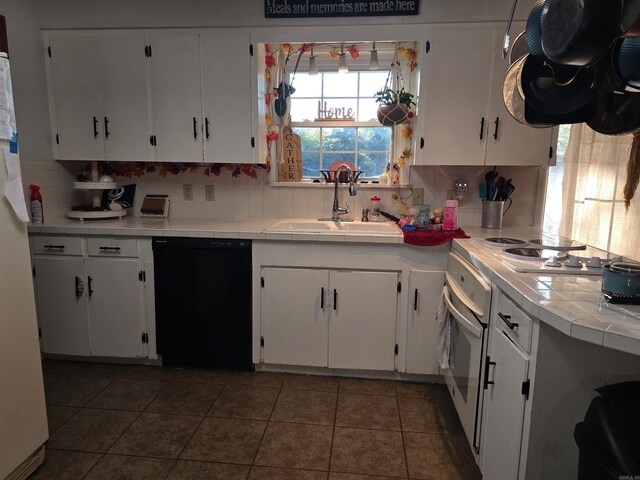 kitchen featuring decorative backsplash, white cabinets, black dishwasher, and tile counters