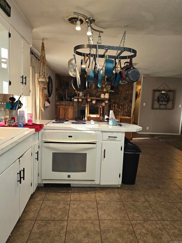 kitchen featuring white cabinetry, kitchen peninsula, tile counters, and white stove