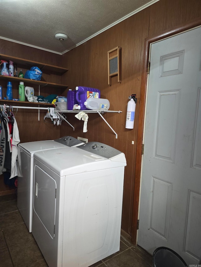 washroom with wood walls, ornamental molding, dark tile patterned floors, a textured ceiling, and washer and dryer