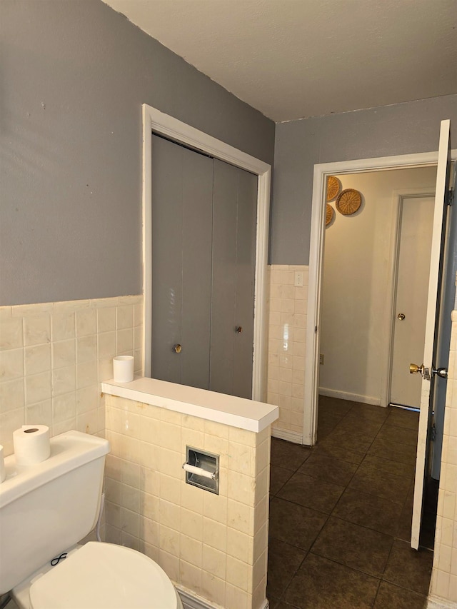 bathroom with tile walls, tile patterned flooring, and toilet