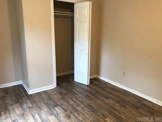 unfurnished bedroom featuring a closet and dark hardwood / wood-style floors