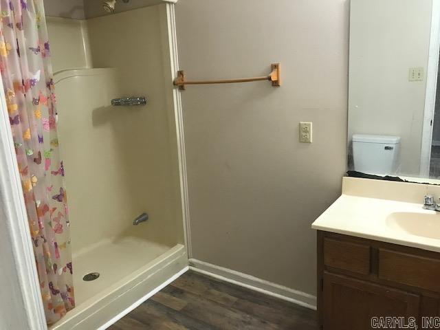 bathroom featuring curtained shower, hardwood / wood-style floors, vanity, and toilet