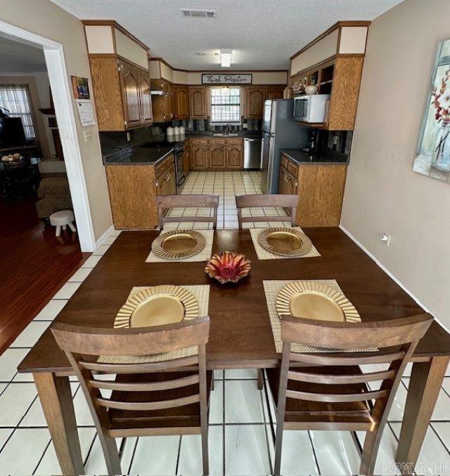 dining room with a textured ceiling, light tile patterned floors, and a healthy amount of sunlight