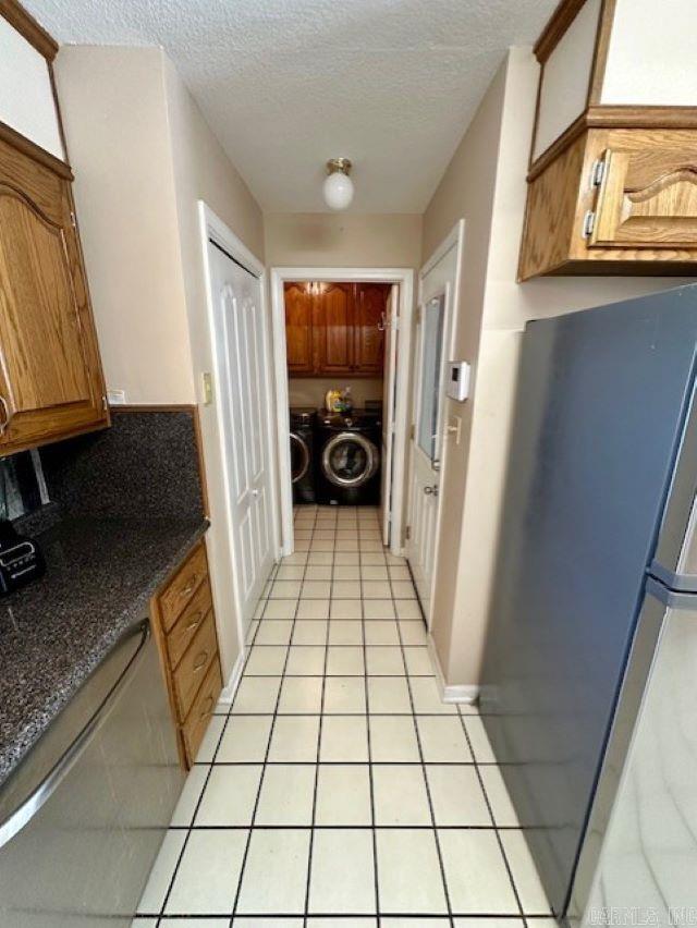 kitchen featuring stainless steel appliances, light tile patterned flooring, separate washer and dryer, a textured ceiling, and backsplash