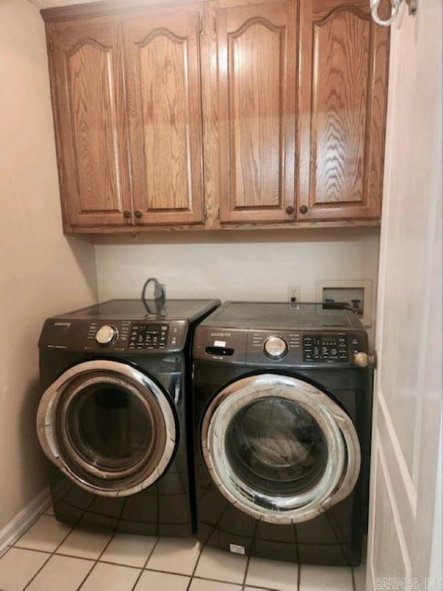 clothes washing area featuring cabinets, washer and clothes dryer, and light tile patterned floors