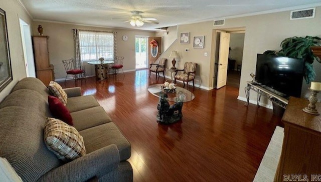 living room with dark wood-type flooring, ceiling fan, a textured ceiling, and ornamental molding