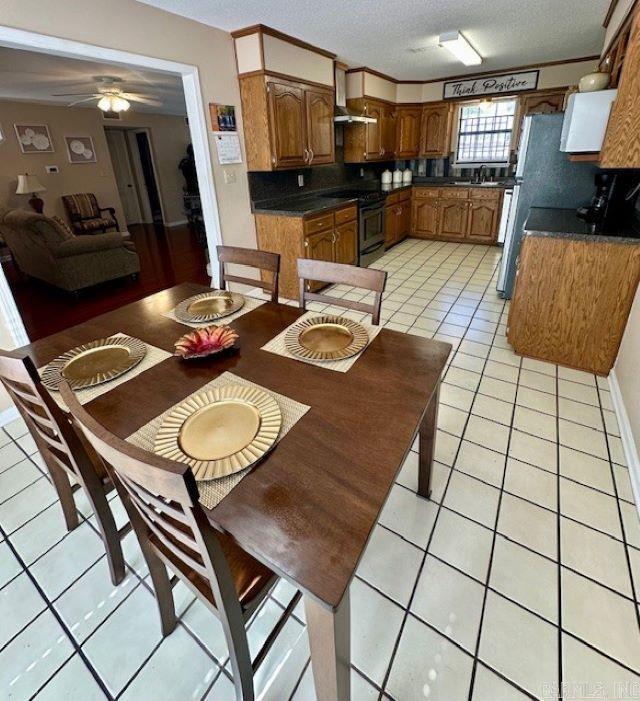 dining area featuring a textured ceiling, sink, light tile patterned floors, ceiling fan, and crown molding