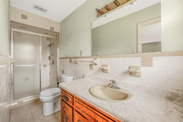 bathroom featuring tile walls, a shower with door, tile patterned floors, vanity, and toilet