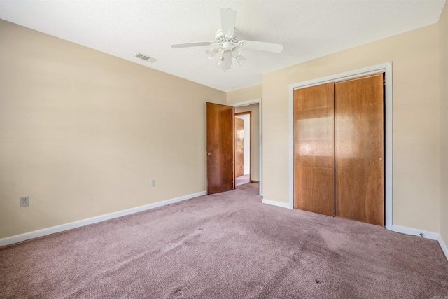 unfurnished bedroom featuring a textured ceiling, light carpet, ceiling fan, and a closet