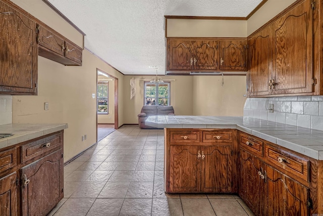 kitchen with a textured ceiling, kitchen peninsula, and tile countertops