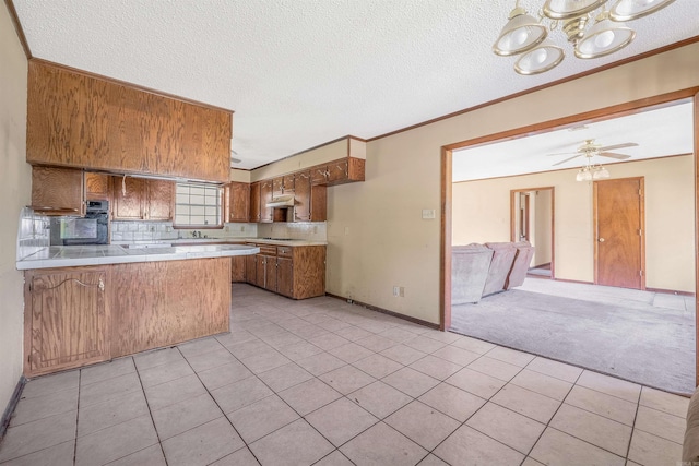 kitchen featuring ceiling fan, kitchen peninsula, a textured ceiling, backsplash, and light carpet