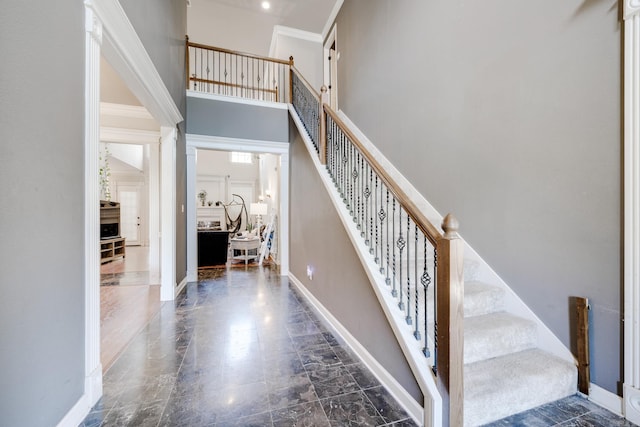 staircase with a towering ceiling and crown molding