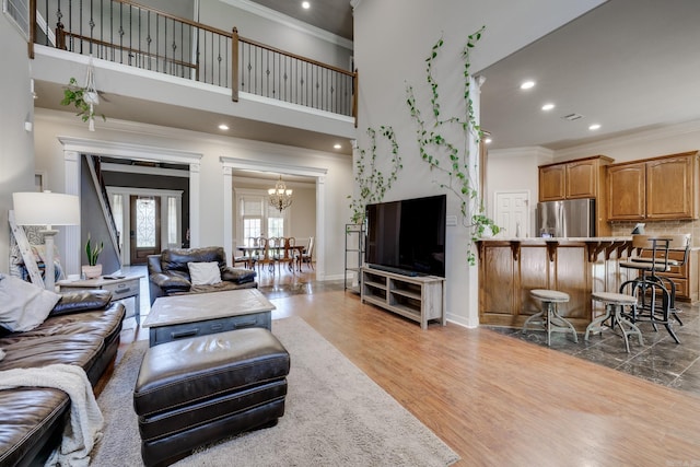 living room with a towering ceiling, crown molding, hardwood / wood-style floors, and a chandelier