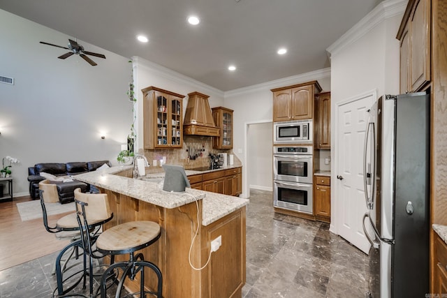 kitchen with a kitchen breakfast bar, tasteful backsplash, kitchen peninsula, stainless steel appliances, and premium range hood