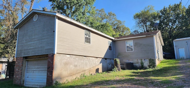 rear view of property featuring a garage and central air condition unit