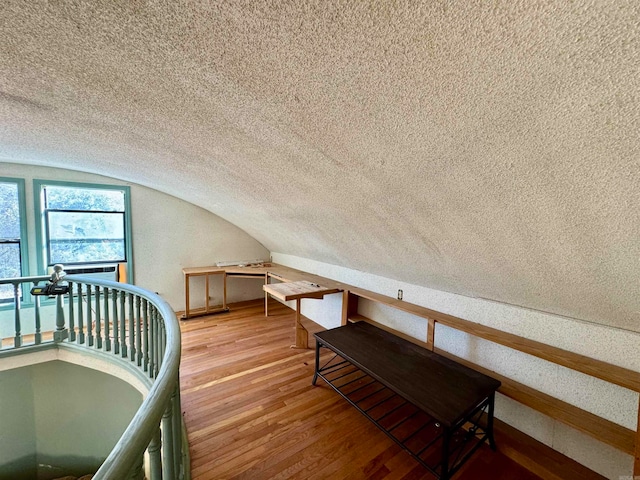 bonus room with lofted ceiling, a textured ceiling, and hardwood / wood-style floors