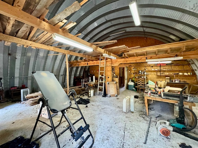 miscellaneous room with lofted ceiling, a workshop area, and concrete floors