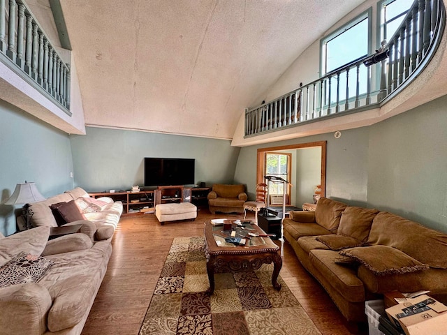 living room featuring high vaulted ceiling, a textured ceiling, and hardwood / wood-style floors